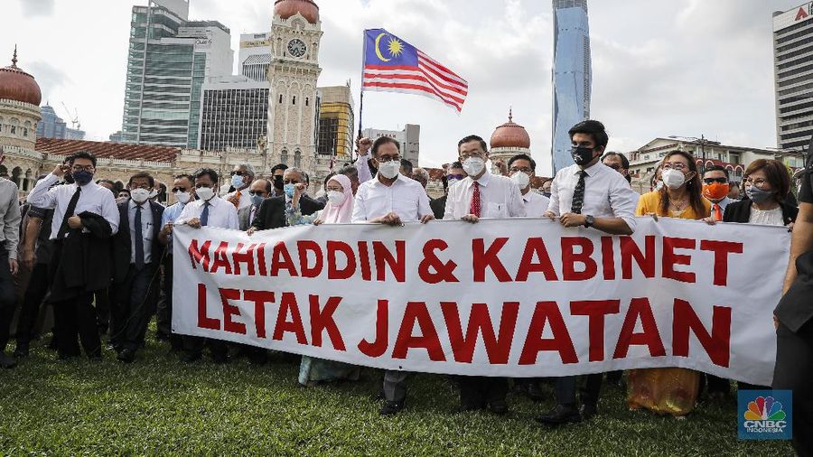 Malaysian opposition members Anwar Ibrahim, fourth from left, and Mahathir Mohamad, second from left in blue mask, hold a banner reading