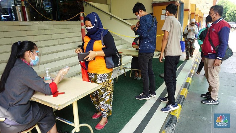 Petugas mengecek kartu vaksin pengunjung yang akan masuk kedalam mal ITC Fatmawati, Selasa (3/8/2021). Pengelola pusat perbelanjaan mendukung rencana masuk mal harus menunjukkan setifikat vaksin, hal ini dinilai dapat mempercepat program vaksinasi Covid-19 dan untuk mencapai kekebalan kelompok (herd immunity). (CNBC Indonesia/Tri Susilo)