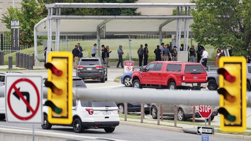 A police officer looks at a vehicle outside the Pentagon, Tuesday, Aug. 3, 2021 in Washington. Gunshots were fired Tuesday morning near the entrance of the Pentagon, resulting in multiple injuries. The facility, the headquarters of the U.S. military, was placed on lockdown. The incident occurred on a Metro bus platform that is part of the Pentagon Transit Center, the Pentagon Protection Force Protection Agency tweeted. (AP Photo/Andrew Harnik)