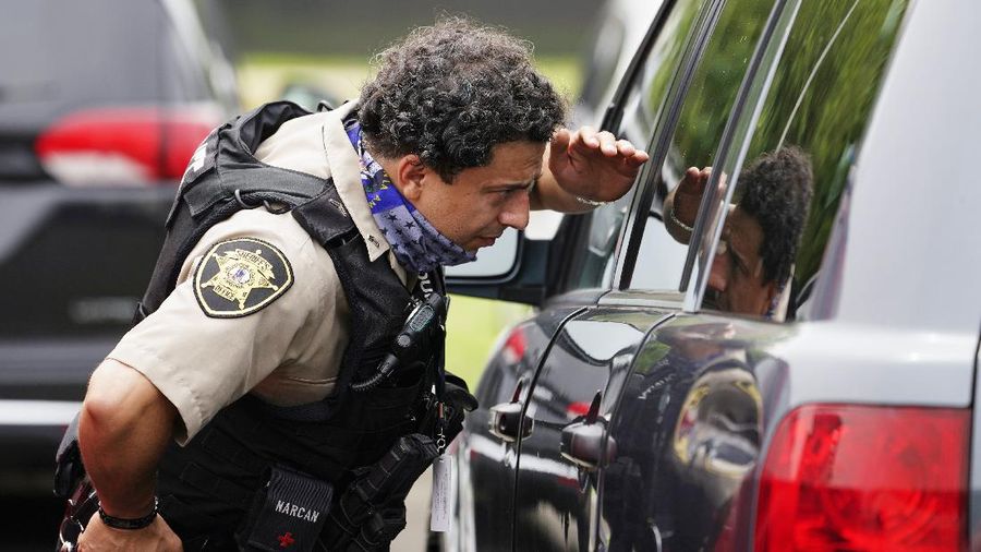 A police officer looks at a vehicle outside the Pentagon, Tuesday, Aug. 3, 2021 in Washington. Gunshots were fired Tuesday morning near the entrance of the Pentagon, resulting in multiple injuries. The facility, the headquarters of the U.S. military, was placed on lockdown. The incident occurred on a Metro bus platform that is part of the Pentagon Transit Center, the Pentagon Protection Force Protection Agency tweeted. (AP Photo/Andrew Harnik)