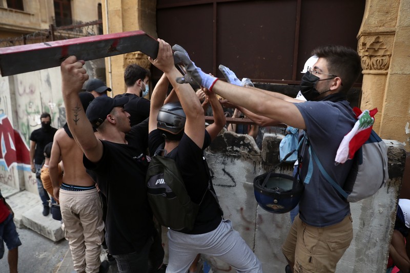 APTOPIX Lebanon An anti-government protester flashes the victory sign amid tear gas fired by riot police during a protest marking the first anniversary of the massive blast at Beirut's port, near Parliament Square, In Beirut, Lebanon, Wednesday, Aug. 4, 2021. United in grief and anger, families of the victims and other Lebanese came out into the streets of Beirut on Wednesday to demand accountability as banks, businesses and government offices shuttered to mark one year since the horrific explosion. (AP Photo/Bilal Hussein)
