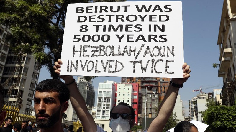 An anti-government protester flashes the victory sign amid tear gas fired by riot police during a protest marking the first anniversary of the massive blast at Beirut's port, near Parliament Square, In Beirut, Lebanon, Wednesday, Aug. 4, 2021. United in grief and anger, families of the victims and other Lebanese came out into the streets of Beirut on Wednesday to demand accountability as banks, businesses and government offices shuttered to mark one year since the horrific explosion. (AP Photo/Bilal Hussein)