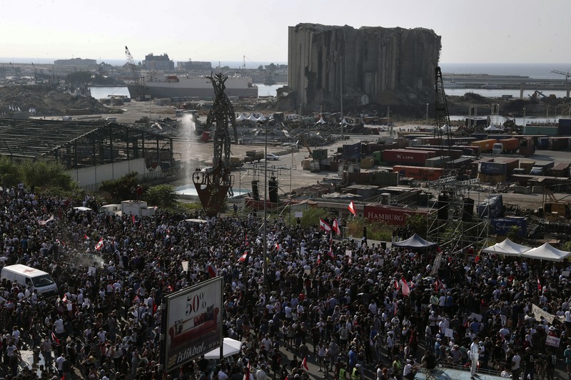 An anti-government protester flashes the victory sign amid tear gas fired by riot police during a protest marking the first anniversary of the massive blast at Beirut's port, near Parliament Square, In Beirut, Lebanon, Wednesday, Aug. 4, 2021. United in grief and anger, families of the victims and other Lebanese came out into the streets of Beirut on Wednesday to demand accountability as banks, businesses and government offices shuttered to mark one year since the horrific explosion. (AP Photo/Bilal Hussein)