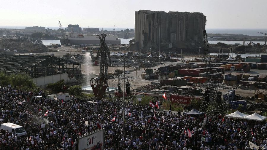 An anti-government protester flashes the victory sign amid tear gas fired by riot police during a protest marking the first anniversary of the massive blast at Beirut's port, near Parliament Square, In Beirut, Lebanon, Wednesday, Aug. 4, 2021. United in grief and anger, families of the victims and other Lebanese came out into the streets of Beirut on Wednesday to demand accountability as banks, businesses and government offices shuttered to mark one year since the horrific explosion. (AP Photo/Bilal Hussein)
