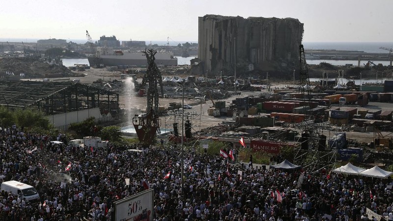 An anti-government protester flashes the victory sign amid tear gas fired by riot police during a protest marking the first anniversary of the massive blast at Beirut's port, near Parliament Square, In Beirut, Lebanon, Wednesday, Aug. 4, 2021. United in grief and anger, families of the victims and other Lebanese came out into the streets of Beirut on Wednesday to demand accountability as banks, businesses and government offices shuttered to mark one year since the horrific explosion. (AP Photo/Bilal Hussein)