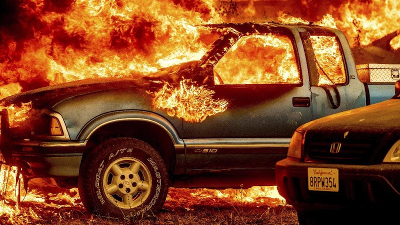 Flames from the Dixie Fire consume a pickup truck on Highway 89 south of Greenville on Thursday, Aug. 5, 2021, in Plumas County, Calif. (AP Photo/Noah Berger)