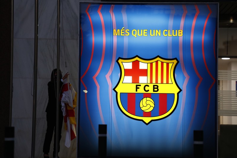 Spain Soccer Barcelona Messi A fan wearing the number 10 Lionel Messi replica shirt sits outside the club offices with others in Barcelona, Spain, Thursday, Aug. 5, 2021. Barcelona announced Thursday that Messi will not stay with the club, saying that the Spanish league's financial regulations made it impossible to sign the Argentina star to a new contract. (AP Photo/Joan Monfort)
