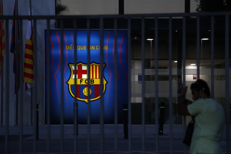 Spain Soccer Barcelona Messi A fan wearing the number 10 Lionel Messi replica shirt sits outside the club offices with others in Barcelona, Spain, Thursday, Aug. 5, 2021. Barcelona announced Thursday that Messi will not stay with the club, saying that the Spanish league's financial regulations made it impossible to sign the Argentina star to a new contract. (AP Photo/Joan Monfort)