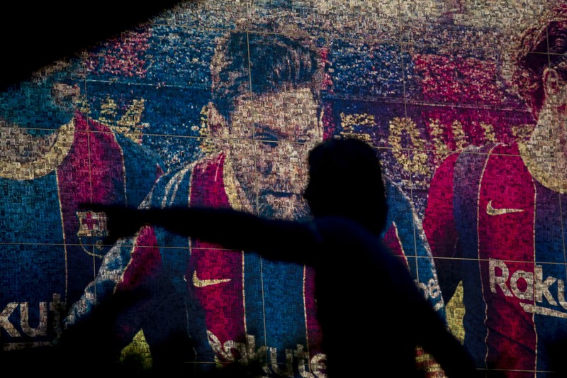 Spain Soccer Barcelona Messi A fan wearing the number 10 Lionel Messi replica shirt sits outside the club offices with others in Barcelona, Spain, Thursday, Aug. 5, 2021. Barcelona announced Thursday that Messi will not stay with the club, saying that the Spanish league's financial regulations made it impossible to sign the Argentina star to a new contract. (AP Photo/Joan Monfort)