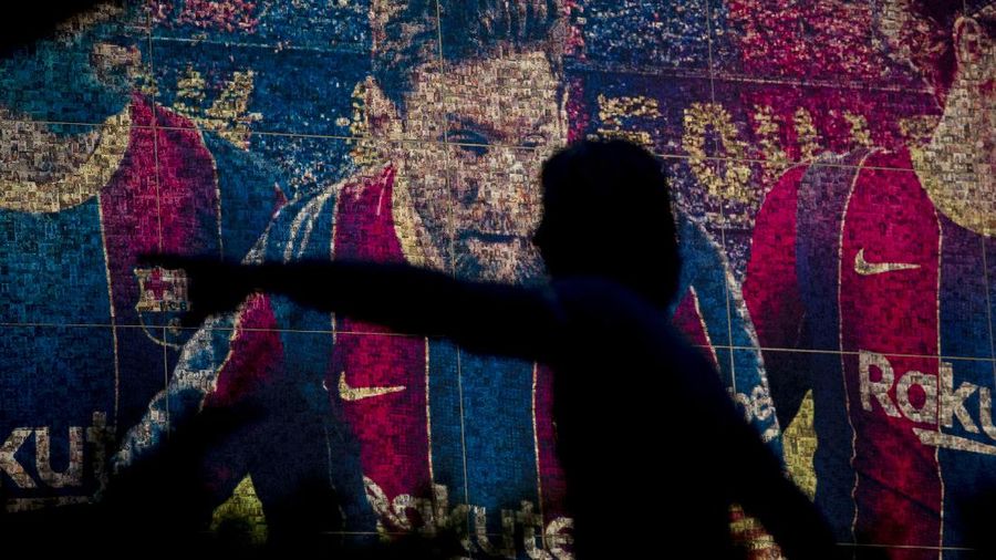 A fan wearing the number 10 Lionel Messi replica shirt sits outside the club offices with others in Barcelona, Spain, Thursday, Aug. 5, 2021. Barcelona announced Thursday that Messi will not stay with the club, saying that the Spanish league's financial regulations made it impossible to sign the Argentina star to a new contract. (AP Photo/Joan Monfort)