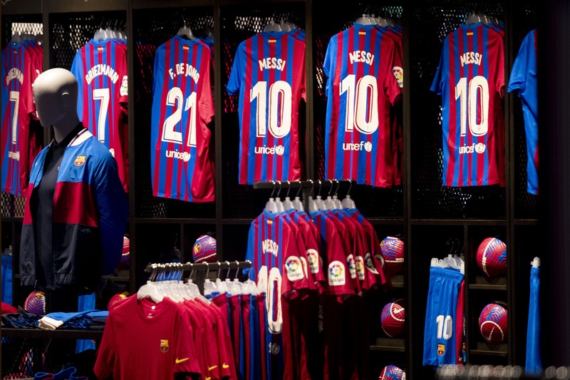 Spain Soccer Barcelona Messi A fan wearing the number 10 Lionel Messi replica shirt sits outside the club offices with others in Barcelona, Spain, Thursday, Aug. 5, 2021. Barcelona announced Thursday that Messi will not stay with the club, saying that the Spanish league's financial regulations made it impossible to sign the Argentina star to a new contract. (AP Photo/Joan Monfort)