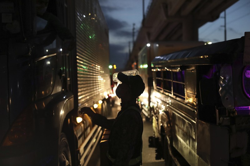 A woman crosses a highway as traffic builds up near a checkpoint during a stricter lockdown as a precaution against the spread of the coronavirus on the outskirts of Marikina City, Philippines on Friday, August 6, 2021. Thousands of people jammed coronavirus vaccination centers in the Philippine capital, defying social distancing restrictions, after false news spread that unvaccinated residents would be deprived of cash aid or barred from leaving home during a two-week lockdown that started Friday. (AP Photo/Basilio Sepe)