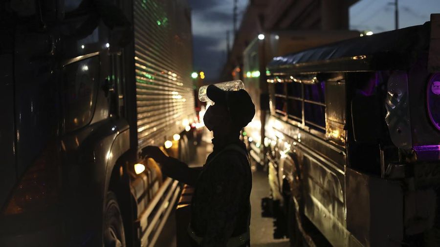 A woman crosses a highway as traffic builds up near a checkpoint during a stricter lockdown as a precaution against the spread of the coronavirus on the outskirts of Marikina City, Philippines on Friday, August 6, 2021. Thousands of people jammed coronavirus vaccination centers in the Philippine capital, defying social distancing restrictions, after false news spread that unvaccinated residents would be deprived of cash aid or barred from leaving home during a two-week lockdown that started Friday. (AP Photo/Basilio Sepe)