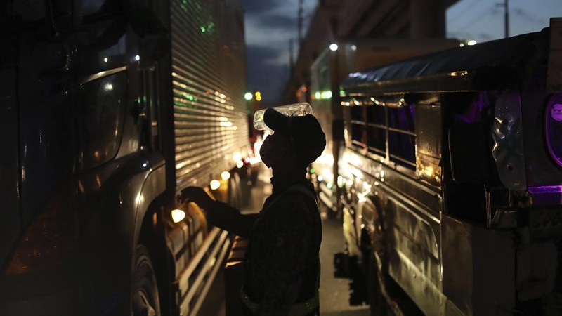 A woman crosses a highway as traffic builds up near a checkpoint during a stricter lockdown as a precaution against the spread of the coronavirus on the outskirts of Marikina City, Philippines on Friday, August 6, 2021. Thousands of people jammed coronavirus vaccination centers in the Philippine capital, defying social distancing restrictions, after false news spread that unvaccinated residents would be deprived of cash aid or barred from leaving home during a two-week lockdown that started Friday. (AP Photo/Basilio Sepe)