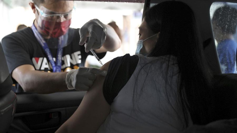 A woman receives a shot of the Pfizer COVID-19 vaccine at a drive-thru vaccination site during a stricter lockdown in Manila, Philippines on Friday. August 6, 2021. Thousands of people jammed coronavirus vaccination centers in the Philippine capital, defying social distancing restrictions, after false news spread that unvaccinated residents would be deprived of cash aid or barred from leaving home during a two-week lockdown that started Friday. (AP Photo/Basilio Sepe)