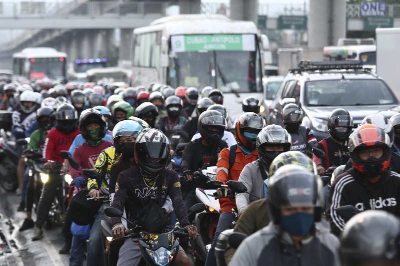 A woman crosses a highway as traffic builds up near a checkpoint during a stricter lockdown as a precaution against the spread of the coronavirus on the outskirts of Marikina City, Philippines on Friday, August 6, 2021. Thousands of people jammed coronavirus vaccination centers in the Philippine capital, defying social distancing restrictions, after false news spread that unvaccinated residents would be deprived of cash aid or barred from leaving home during a two-week lockdown that started Friday. (AP Photo/Basilio Sepe)