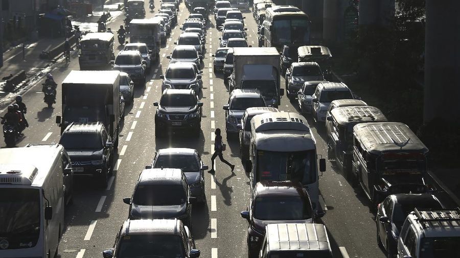 A woman crosses a highway as traffic builds up near a checkpoint during a stricter lockdown as a precaution against the spread of the coronavirus on the outskirts of Marikina City, Philippines on Friday, August 6, 2021. Thousands of people jammed coronavirus vaccination centers in the Philippine capital, defying social distancing restrictions, after false news spread that unvaccinated residents would be deprived of cash aid or barred from leaving home during a two-week lockdown that started Friday. (AP Photo/Basilio Sepe)