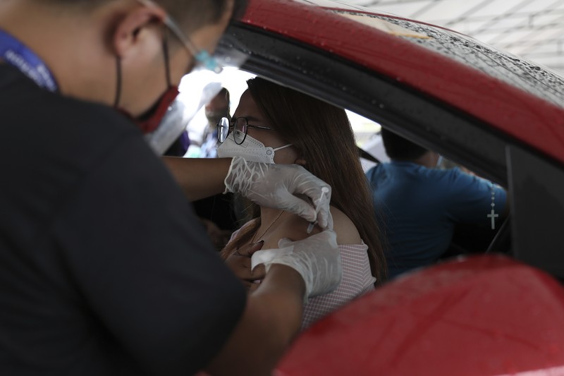 A woman crosses a highway as traffic builds up near a checkpoint during a stricter lockdown as a precaution against the spread of the coronavirus on the outskirts of Marikina City, Philippines on Friday, August 6, 2021. Thousands of people jammed coronavirus vaccination centers in the Philippine capital, defying social distancing restrictions, after false news spread that unvaccinated residents would be deprived of cash aid or barred from leaving home during a two-week lockdown that started Friday. (AP Photo/Basilio Sepe)