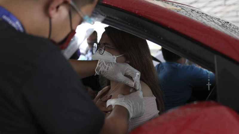 A woman crosses a highway as traffic builds up near a checkpoint during a stricter lockdown as a precaution against the spread of the coronavirus on the outskirts of Marikina City, Philippines on Friday, August 6, 2021. Thousands of people jammed coronavirus vaccination centers in the Philippine capital, defying social distancing restrictions, after false news spread that unvaccinated residents would be deprived of cash aid or barred from leaving home during a two-week lockdown that started Friday. (AP Photo/Basilio Sepe)