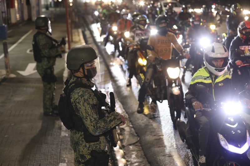 A woman crosses a highway as traffic builds up near a checkpoint during a stricter lockdown as a precaution against the spread of the coronavirus on the outskirts of Marikina City, Philippines on Friday, August 6, 2021. Thousands of people jammed coronavirus vaccination centers in the Philippine capital, defying social distancing restrictions, after false news spread that unvaccinated residents would be deprived of cash aid or barred from leaving home during a two-week lockdown that started Friday. (AP Photo/Basilio Sepe)