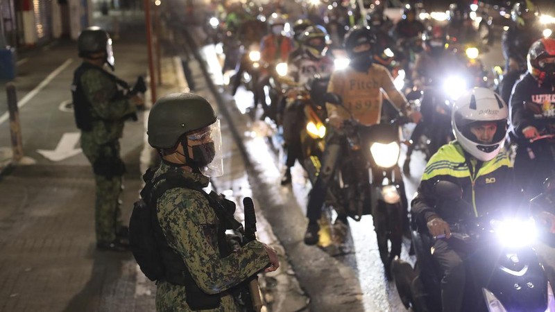 A woman crosses a highway as traffic builds up near a checkpoint during a stricter lockdown as a precaution against the spread of the coronavirus on the outskirts of Marikina City, Philippines on Friday, August 6, 2021. Thousands of people jammed coronavirus vaccination centers in the Philippine capital, defying social distancing restrictions, after false news spread that unvaccinated residents would be deprived of cash aid or barred from leaving home during a two-week lockdown that started Friday. (AP Photo/Basilio Sepe)