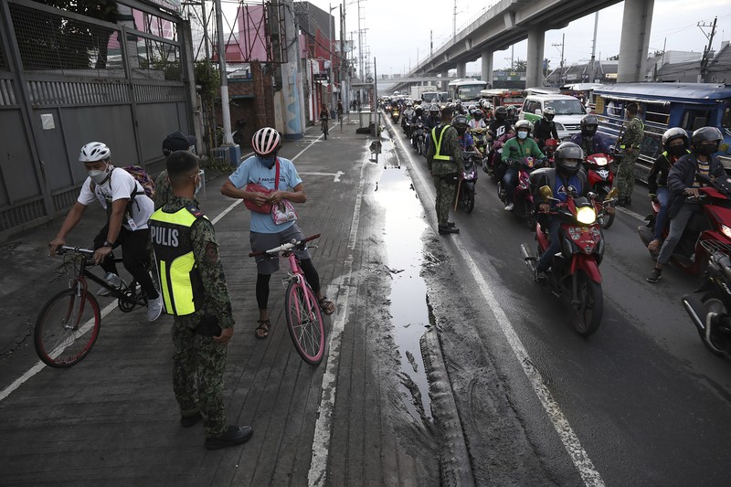 Virus Outbreak Philippines A woman crosses a highway as traffic builds up near a checkpoint during a stricter lockdown as a precaution against the spread of the coronavirus on the outskirts of Marikina City, Philippines on Friday, August 6, 2021. Thousands of people jammed coronavirus vaccination centers in the Philippine capital, defying social distancing restrictions, after false news spread that unvaccinated residents would be deprived of cash aid or barred from leaving home during a two-week lockdown that started Friday. (AP Photo/Basilio Sepe)