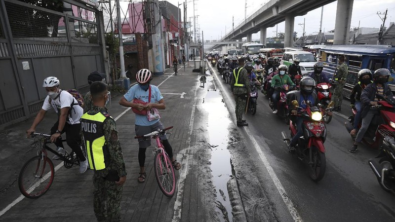 A woman crosses a highway as traffic builds up near a checkpoint during a stricter lockdown as a precaution against the spread of the coronavirus on the outskirts of Marikina City, Philippines on Friday, August 6, 2021. Thousands of people jammed coronavirus vaccination centers in the Philippine capital, defying social distancing restrictions, after false news spread that unvaccinated residents would be deprived of cash aid or barred from leaving home during a two-week lockdown that started Friday. (AP Photo/Basilio Sepe)