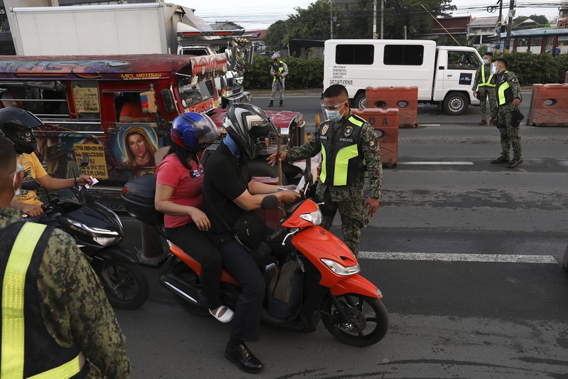 A woman crosses a highway as traffic builds up near a checkpoint during a stricter lockdown as a precaution against the spread of the coronavirus on the outskirts of Marikina City, Philippines on Friday, August 6, 2021. Thousands of people jammed coronavirus vaccination centers in the Philippine capital, defying social distancing restrictions, after false news spread that unvaccinated residents would be deprived of cash aid or barred from leaving home during a two-week lockdown that started Friday. (AP Photo/Basilio Sepe)