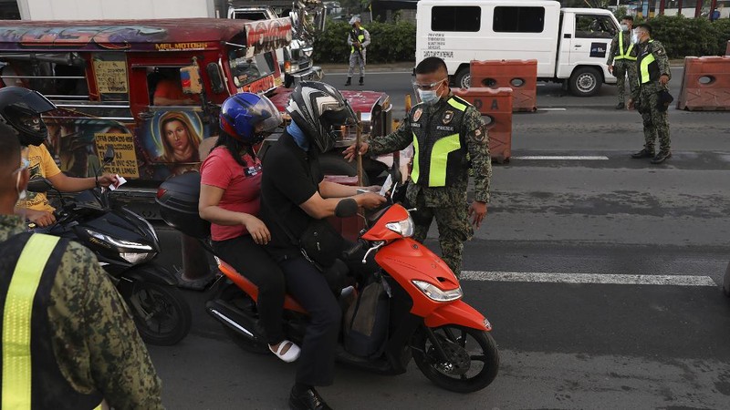 A woman crosses a highway as traffic builds up near a checkpoint during a stricter lockdown as a precaution against the spread of the coronavirus on the outskirts of Marikina City, Philippines on Friday, August 6, 2021. Thousands of people jammed coronavirus vaccination centers in the Philippine capital, defying social distancing restrictions, after false news spread that unvaccinated residents would be deprived of cash aid or barred from leaving home during a two-week lockdown that started Friday. (AP Photo/Basilio Sepe)
