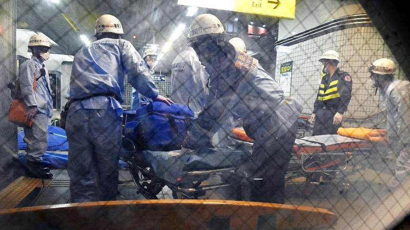 Rescuers carry an injured passenger on  stretcher at Soshigaya Okura Station after stabbing on a commuter train, in Tokyo Friday night, Aug. 6, 2021. A man with a knife attacked 10 passengers on a commuter train in Tokyo on Friday and was arrested by police after fleeing, fire department officials and news reports said. (Kyodo News via AP)