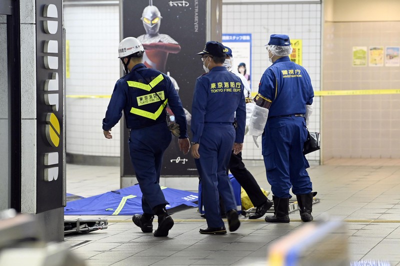 Penusukan di Tokyo Jepang Rescuers carry an injured passenger on stretcher at Soshigaya Okura Station after stabbing on a commuter train, in Tokyo Friday night, Aug. 6, 2021. A man with a knife attacked 10 passengers on a commuter train in Tokyo on Friday and was arrested by police after fleeing, fire department officials and news reports said. (Kyodo News via AP)