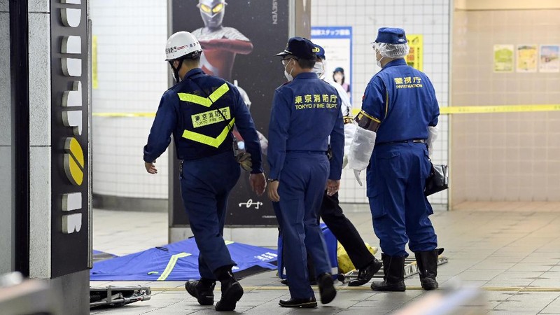 Rescuers carry an injured passenger on  stretcher at Soshigaya Okura Station after stabbing on a commuter train, in Tokyo Friday night, Aug. 6, 2021. A man with a knife attacked 10 passengers on a commuter train in Tokyo on Friday and was arrested by police after fleeing, fire department officials and news reports said. (Kyodo News via AP)
