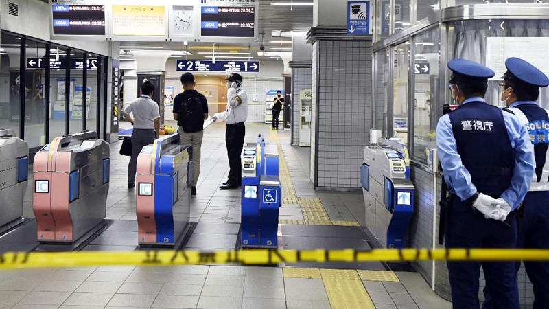 Rescuers carry an injured passenger on  stretcher at Soshigaya Okura Station after stabbing on a commuter train, in Tokyo Friday night, Aug. 6, 2021. A man with a knife attacked 10 passengers on a commuter train in Tokyo on Friday and was arrested by police after fleeing, fire department officials and news reports said. (Kyodo News via AP)