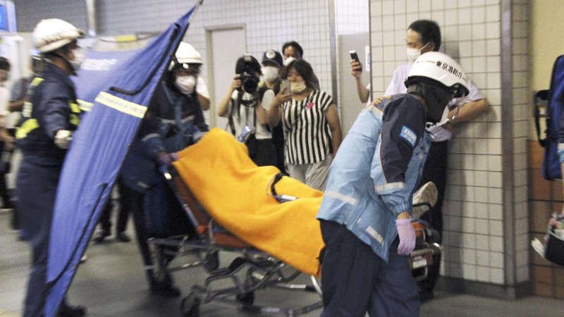Rescuers carry an injured passenger on  stretcher at Soshigaya Okura Station after stabbing on a commuter train, in Tokyo Friday night, Aug. 6, 2021. A man with a knife attacked 10 passengers on a commuter train in Tokyo on Friday and was arrested by police after fleeing, fire department officials and news reports said. (Kyodo News via AP)