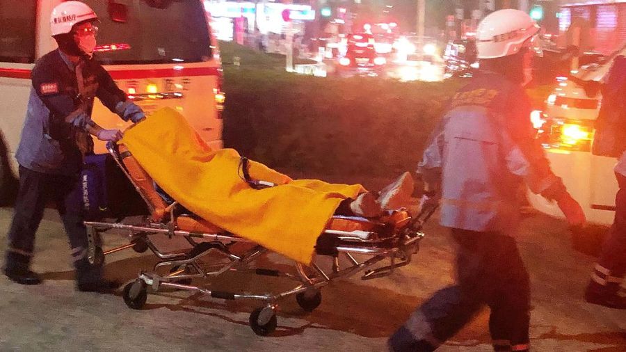 Rescuers carry an injured passenger on  stretcher at Soshigaya Okura Station after stabbing on a commuter train, in Tokyo Friday night, Aug. 6, 2021. A man with a knife attacked 10 passengers on a commuter train in Tokyo on Friday and was arrested by police after fleeing, fire department officials and news reports said. (Kyodo News via AP)