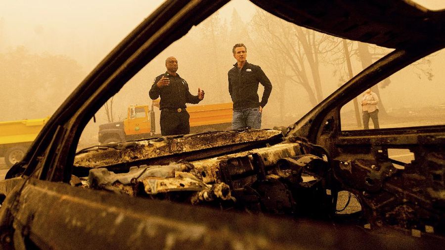 California Gov. Gavin Newsom examines a scorched car while visiting Greenville, which suffered extensive structure loss during the Dixie Fire, on Saturday, Aug. 7, 2021, in Plumas County, Calif. Accompanying him is Cal Fire Assistant Region Chief Curtis Brown. (AP Photo/Noah Berger)