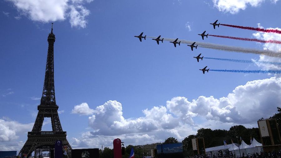 The French Aerial Patrol fly by the Eiffel Tower and over the Olympics fan zone in Paris, Sunday, Aug. 8, 2021. Celebrations were held in Paris Sunday as part of the handover ceremony of Tokyo 2020 to Paris 2024, as Paris will be the next Summer Games host in 2024. The passing of the hosting baton will be split between the Olympic Stadium in Tokyo and a public party and concert in Paris. (AP Photo/Francois Mori)