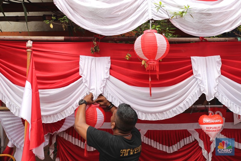 Pedagang memasang pernak pernik bendera di kawasan Pasar Kramat Jati, Jakarta, Senin (9/8/2021). Pedagang mengeluhkan sepinya pembeli, momentum Hari Kemerdekaan RI seharusnya menjadi ladang rezeki dari menjual pernak pernik hiasan bendera merah putih. 
Sahir (25) menjual pernak-pernik bendera sejak tahun 2013 ini mengatakan 