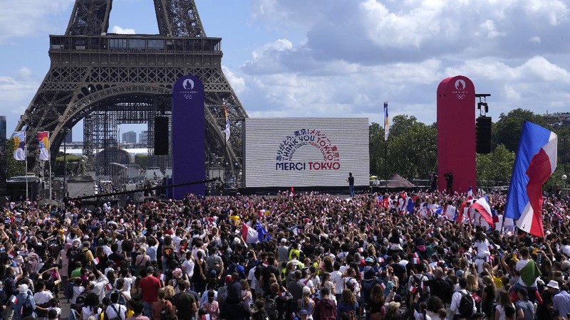 Spectators gather at the Olympics fan zone in the Trocadero Gardens in front of the Eiffel Tower in Paris, Sunday, Aug. 8, 2021. Celebrations were held in Paris Sunday as part of the handover ceremony of Tokyo 2020 to Paris 2024, as Paris will be the next Summer Games host in 2024. The passing of the hosting baton will be split between the Olympic Stadium in Tokyo and a public party and concert in Paris. (AP Photo/Francois Mori)