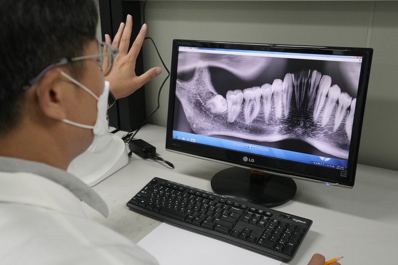 Lee Kyu-chang, a member of the central identification laboratory at the Ministry of National Defense Agency for Killed in Action Recovery & Identification, watches a screen showing dental X-rays of an unidentified soldier killed during the Korean War at the National Cemetery in Seoul, South Korea on July 26, 2021. The Korean War ended 68 years ago, but South Korea is still trying to recover its soldiers' remains. (AP Photo/Ahn Young-joon)