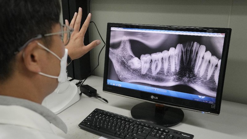 Lee Kyu-chang, a member of the central identification laboratory at the Ministry of National Defense Agency for Killed in Action Recovery & Identification, watches a screen showing dental X-rays of an unidentified soldier killed during the Korean War at the National Cemetery in Seoul, South Korea on July 26, 2021. The Korean War ended 68 years ago, but South Korea is still trying to recover its soldiers' remains. (AP Photo/Ahn Young-joon)