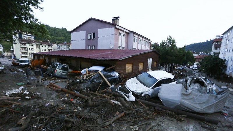 Destroyed cars in a street after floods and mudslides in Bozkurt town of Kastamonu province, Thursday, Aug. 12, 2021. The floods triggered by torrential rains battered the Black Sea coastal provinces of Bartin, Kastamonu, Sinop and Samsun on Wednesday, demolishing homes and bridges and sweeping cars away by torrents. Helicopters scrambled to rescue people stranded on rooftops.(IHA via AP)
