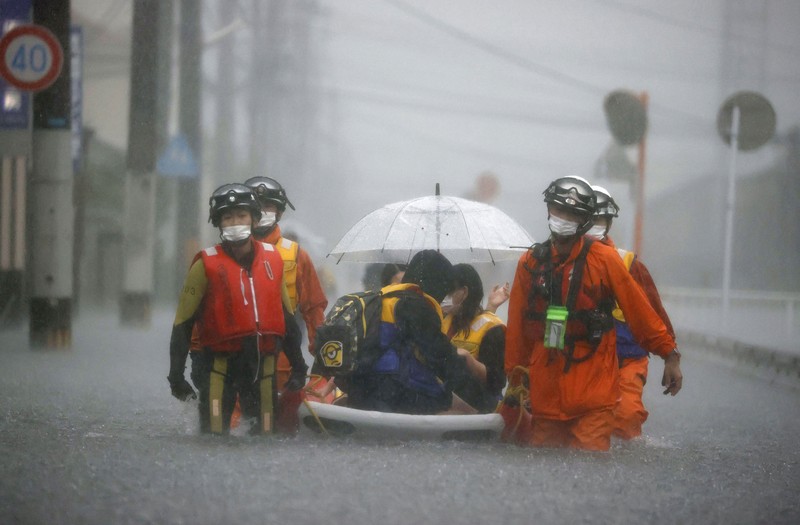 Japan Heavy Rain People wade through a road flooded by heavy rain in Kurume, Fukuoka prefecture, western Japan, Saturday, Aug. 14, 2021. Torrential rain pounding southwestern Japan triggered a mudslide early Friday that swallowed some people and was threatening to cause flooding and more landslides in the region. (Kyodo News via AP)