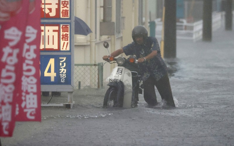 Japan Heavy Rain People wade through a road flooded by heavy rain in Kurume, Fukuoka prefecture, western Japan, Saturday, Aug. 14, 2021. Torrential rain pounding southwestern Japan triggered a mudslide early Friday that swallowed some people and was threatening to cause flooding and more landslides in the region. (Kyodo News via AP)