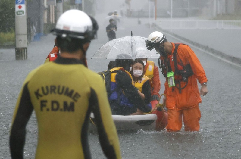 Japan Heavy Rain People wade through a road flooded by heavy rain in Kurume, Fukuoka prefecture, western Japan, Saturday, Aug. 14, 2021. Torrential rain pounding southwestern Japan triggered a mudslide early Friday that swallowed some people and was threatening to cause flooding and more landslides in the region. (Kyodo News via AP)