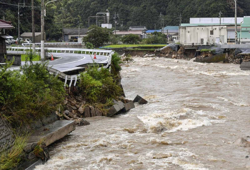 Japan Heavy Rain People wade through a road flooded by heavy rain in Kurume, Fukuoka prefecture, western Japan, Saturday, Aug. 14, 2021. Torrential rain pounding southwestern Japan triggered a mudslide early Friday that swallowed some people and was threatening to cause flooding and more landslides in the region. (Kyodo News via AP)
