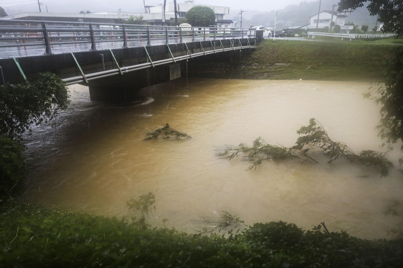 Japan Heavy Rain People wade through a road flooded by heavy rain in Kurume, Fukuoka prefecture, western Japan, Saturday, Aug. 14, 2021. Torrential rain pounding southwestern Japan triggered a mudslide early Friday that swallowed some people and was threatening to cause flooding and more landslides in the region. (Kyodo News via AP)