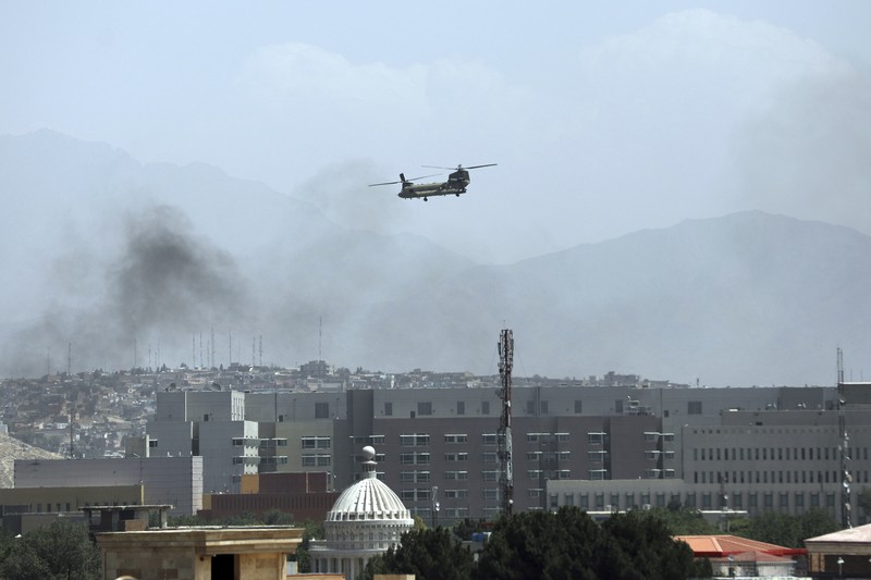 Anti-missile decoy flares are deployed as U.S. Black Hawk military helicopters and a dirigible balloon fly over the city of Kabul, Afghanistan, Sunday, Aug. 15, 2021. Taliban fighters entered the outskirts of the Afghan capital on Sunday and said they were awaiting a “peaceful transfer” of the city after promising not to take it by force, but amid the uncertainty panicked workers fled government offices and helicopters landed at the U.S. Embassy. (AP Photo/Rahmat Gul)