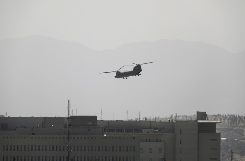 Anti-missile decoy flares are deployed as U.S. Black Hawk military helicopters and a dirigible balloon fly over the city of Kabul, Afghanistan, Sunday, Aug. 15, 2021. Taliban fighters entered the outskirts of the Afghan capital on Sunday and said they were awaiting a “peaceful transfer” of the city after promising not to take it by force, but amid the uncertainty panicked workers fled government offices and helicopters landed at the U.S. Embassy. (AP Photo/Rahmat Gul)