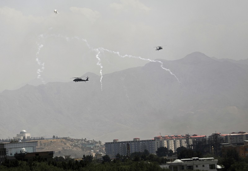 Afghanistan Anti-missile decoy flares are deployed as U.S. Black Hawk military helicopters and a dirigible balloon fly over the city of Kabul, Afghanistan, Sunday, Aug. 15, 2021. Taliban fighters entered the outskirts of the Afghan capital on Sunday and said they were awaiting a “peaceful transfer” of the city after promising not to take it by force, but amid the uncertainty panicked workers fled government offices and helicopters landed at the U.S. Embassy. (AP Photo/Rahmat Gul)